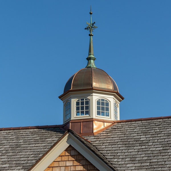 Copper roof cupola with decorative finial against blue sky